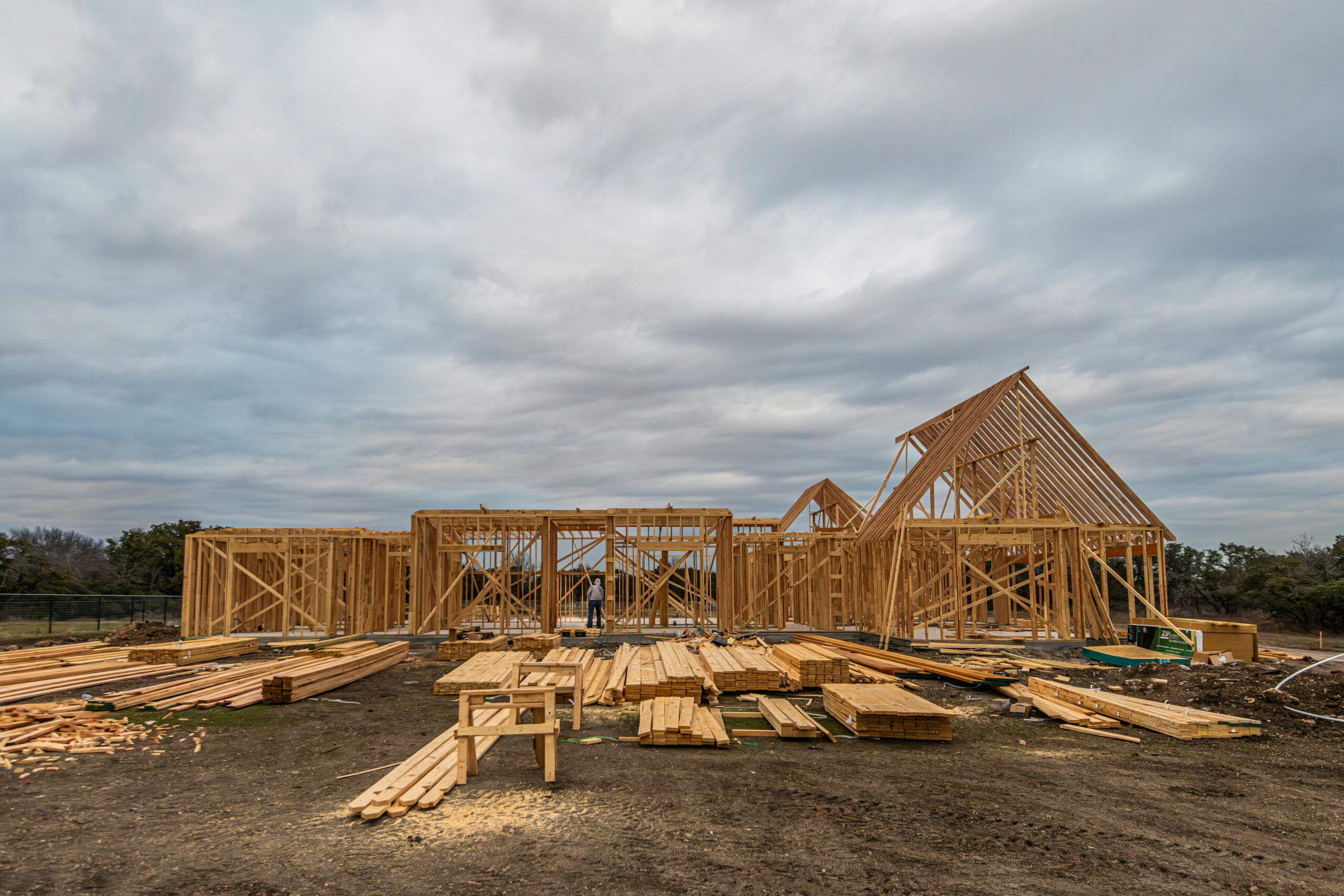 Wooden house framing under construction in Fort Worth, TX during a cloudy day.