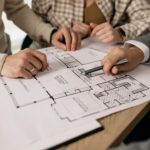 People discuss architectural plans in a real estate planning session, highlighting teamwork.